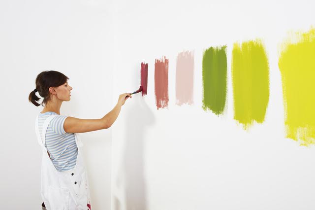 woman painting samples on wall